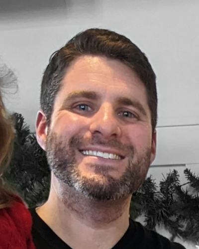 A man smiles while looking at the camera.