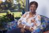 Bernadine “Bernie” McGhee sits smiling in a colorful chair near a window, surrounded by plants. She earned her bachelor’s degree in liberal studies from the University of Kentucky College of Arts and Sciences at age 63.